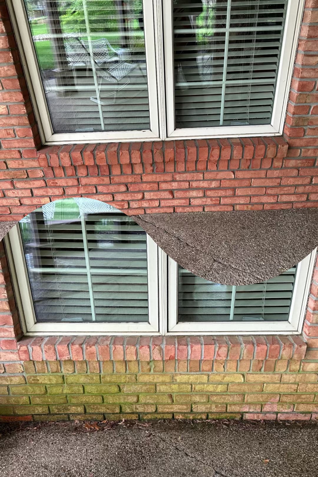 Close-up of a brick wall with two windows, highlighting dirt buildup and clean areas.