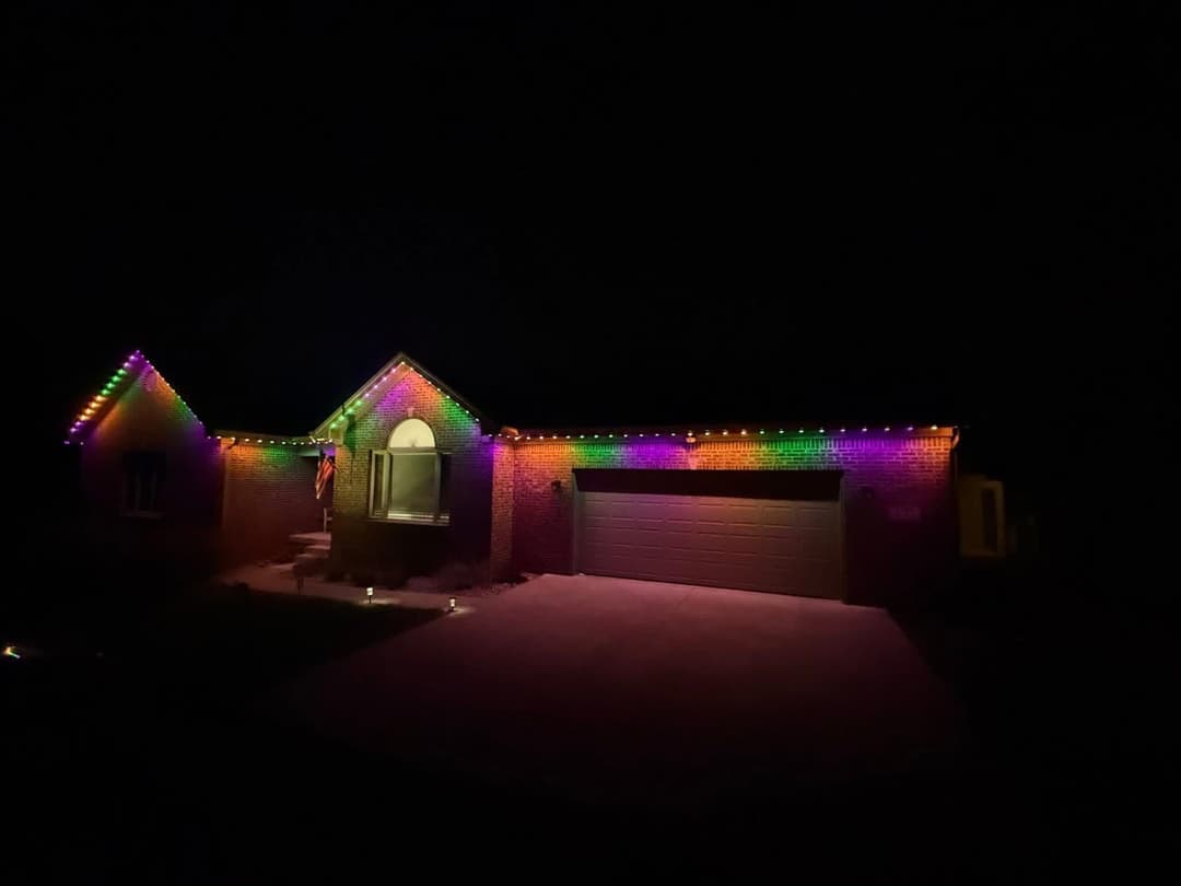 Colorful festive lights illuminate a home at night, creating a cheerful holiday atmosphere.