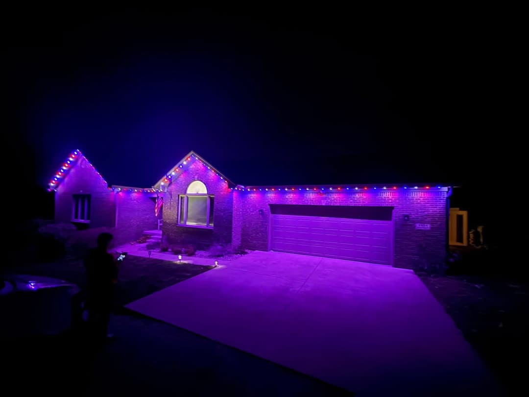 House illuminated with vibrant purple and blue lights during nighttime, creating a festive atmosphere.