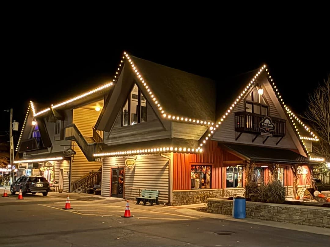 Charming lodge building illuminated with string lights at night, featuring a rustic design.