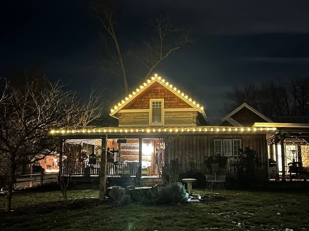 Charming rustic house illuminated with warm string lights during a serene night.