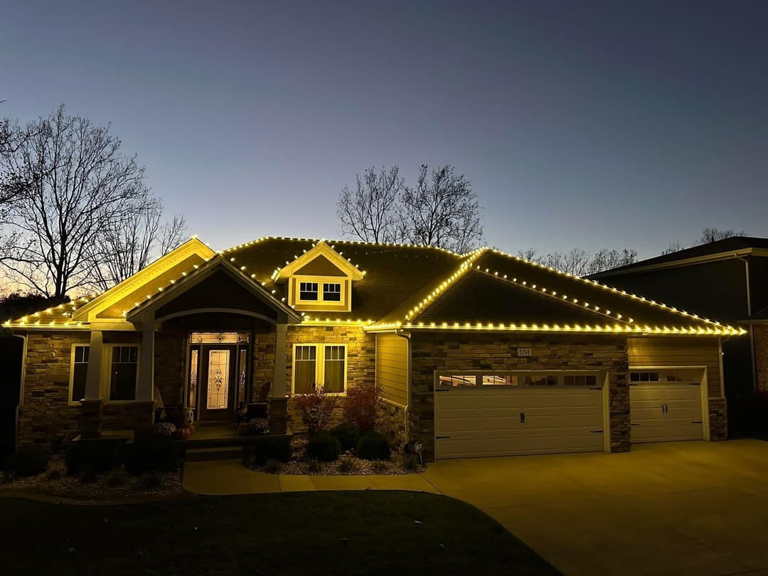 Home decorated with warm white lights during twilight, highlighting its architectural features.